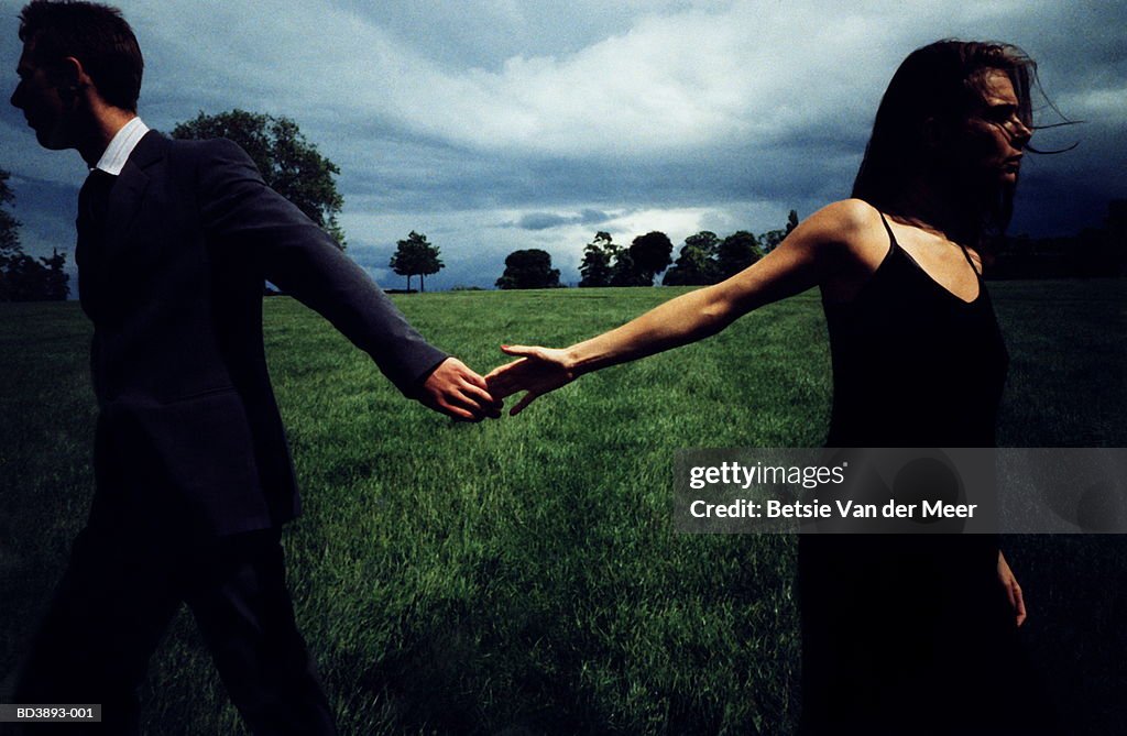 Couple in field, letting go of each other's hands