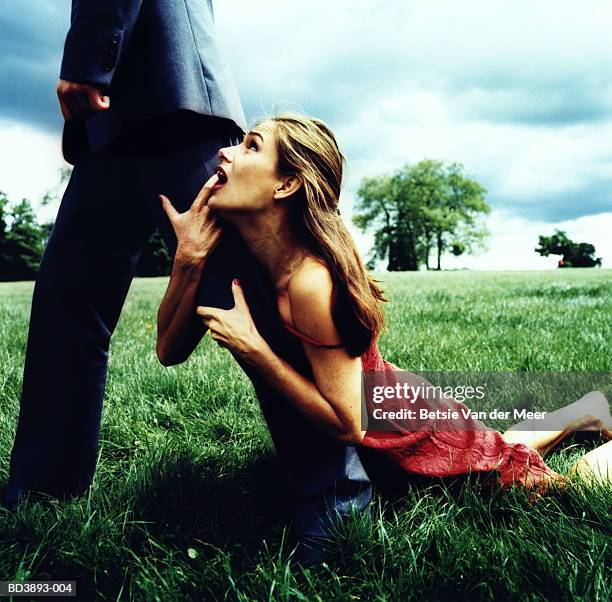 woman holding onto man's leg, as he walks away - man touching womans leg foto e immagini stock