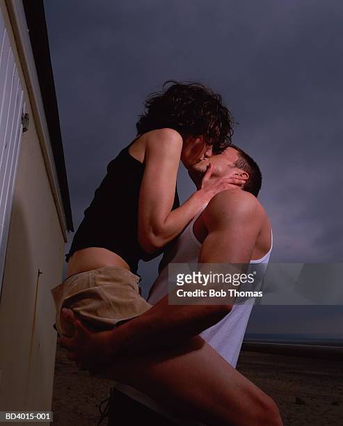 young couple kissing on beach - beach hut foto e immagini stock