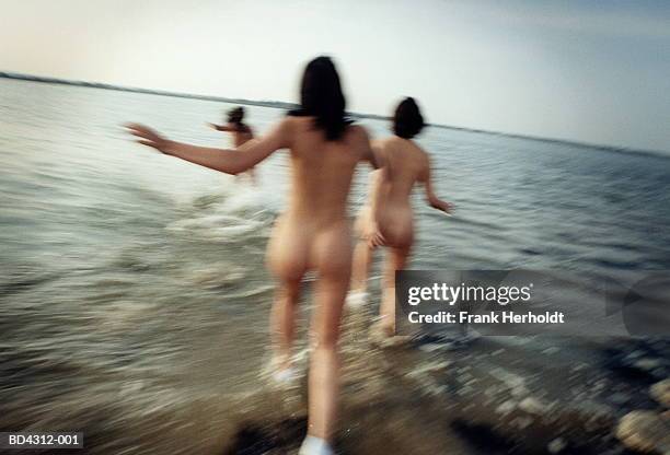 three naked young women running into sea (blurred motion) - non conformity stock pictures, royalty-free photos & images