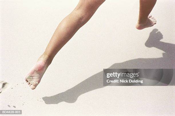 legs running on beach, casting shadow, close-up, low section - barefoot stock pictures, royalty-free photos & images