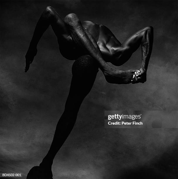 naked male contortionist, leg raised behind head (b&w) - young contortionist stockfoto's en -beelden