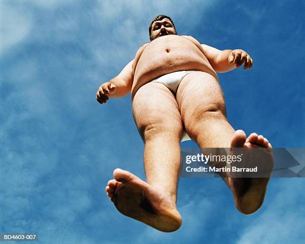 overweight man in underwear, standing on glass, view from below - man looking up imagens e fotografias de stock