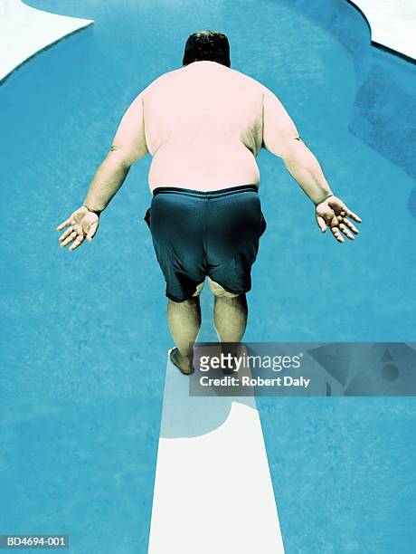 large man standing on edge of diving-board, rear view - trampolino piscina foto e immagini stock