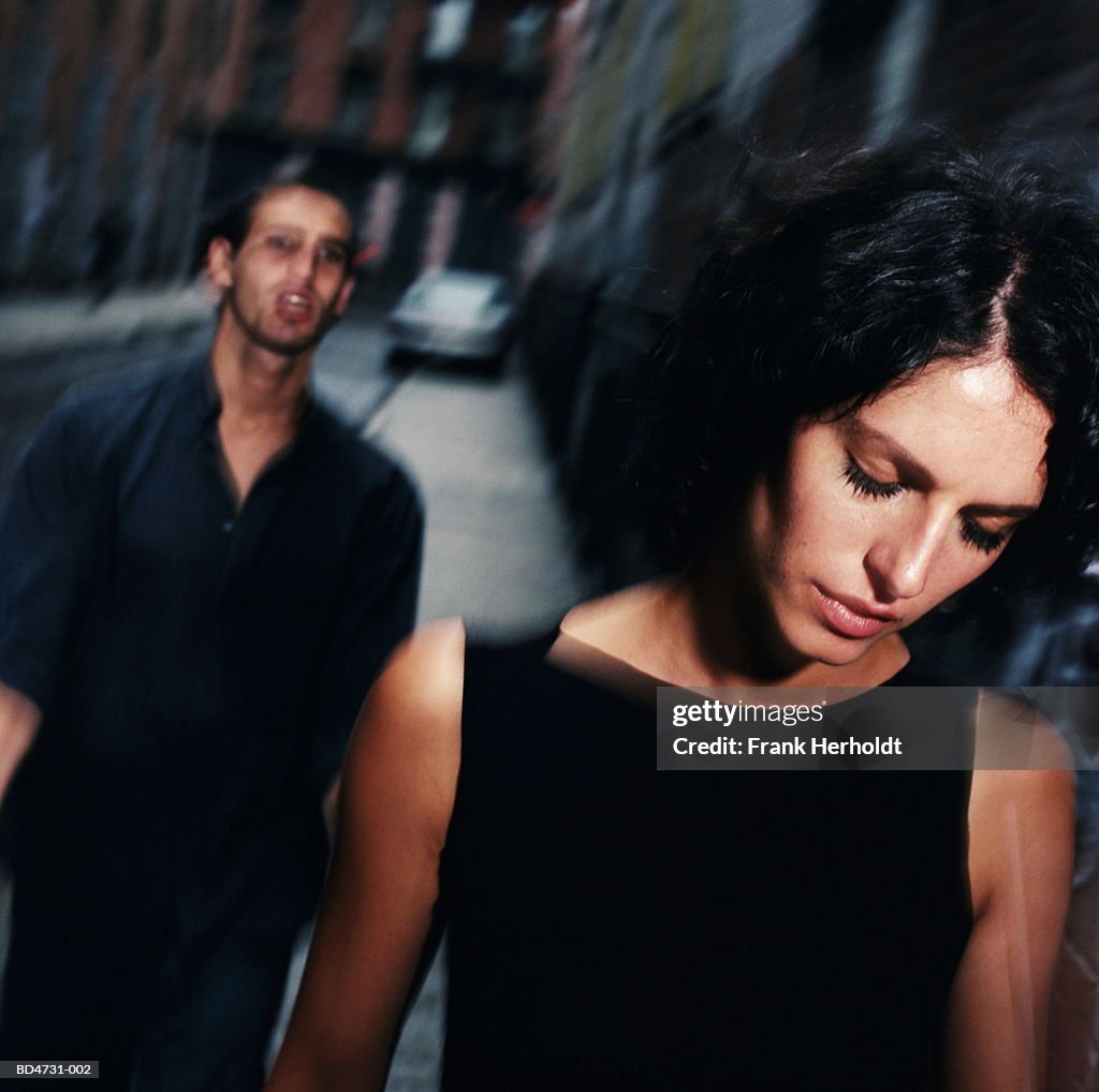 Young man following woman along street (blurred motion)