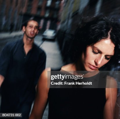 Young man following woman along street (blurred motion) Young man following woman along street (blurred motion)