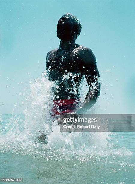 young man jumping out of water (blurred motion) - auftauchen wasser stock-fotos und bilder