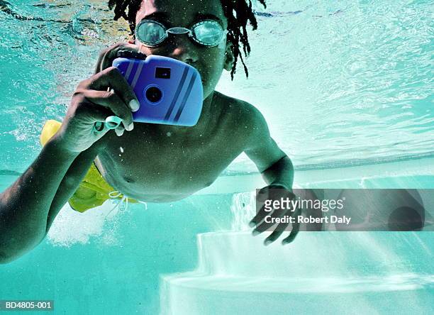 young boy (9-11) using camera in pool, underwater view - macchina fotografica subacquea foto e immagini stock