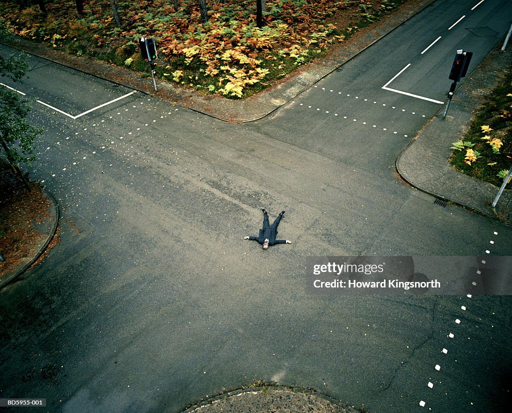 Businessman lying in middle of  crossroads