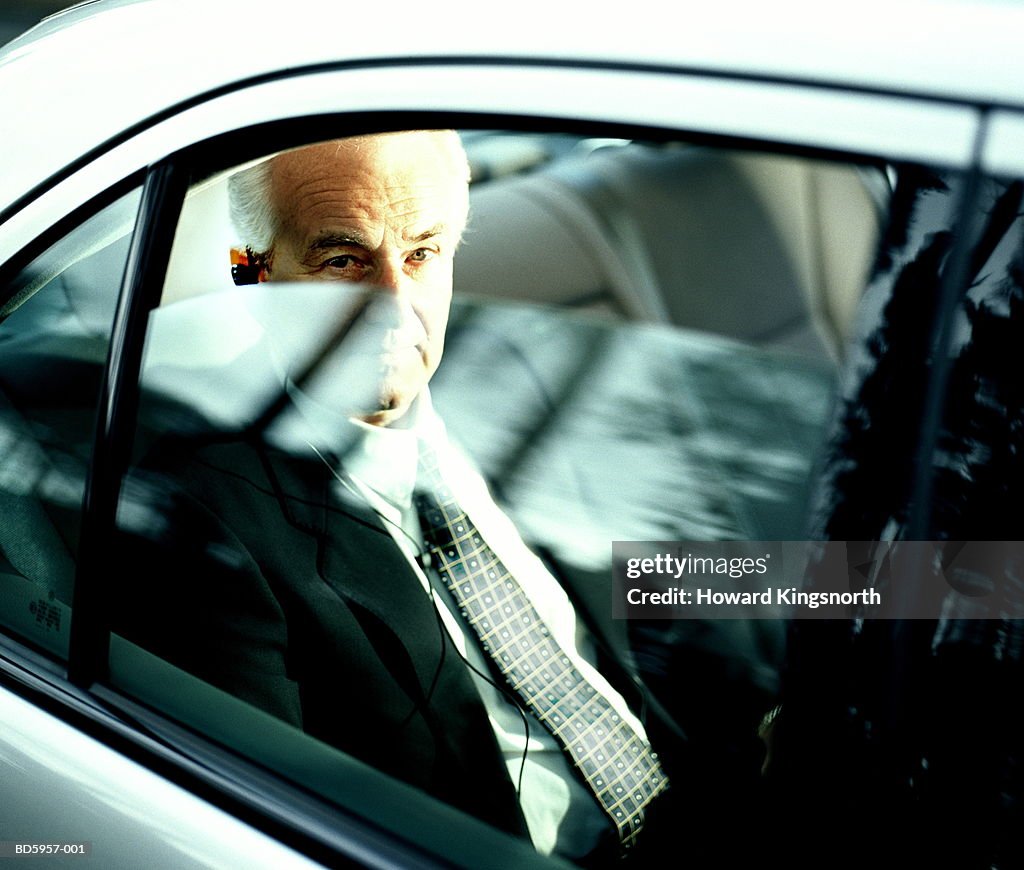 Businessman in back of car, view through window