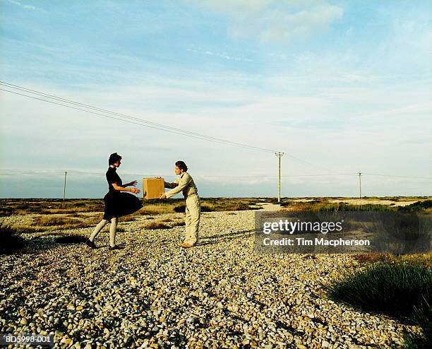 Couple On Road In Landscape Man Passing Box To Woman, Foto de stock