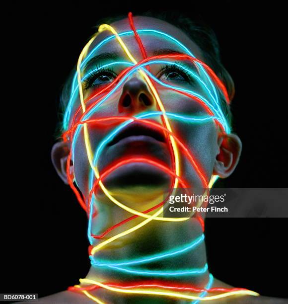 young woman looking up, neon light wires wrapped around face and neck - yellow finch stock pictures, royalty-free photos & images