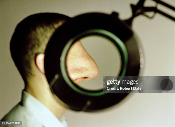 man with nose enlarged through magnifying loupe - human nose stockfoto's en -beelden