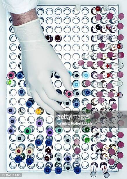 scientist's hand choosing test tube in test tube rack, overhead view - tubos de ensayo fotografías e imágenes de stock