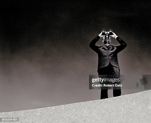 man on wall using binoculars (b&w) - binoculars stock pictures, royalty-free photos & images