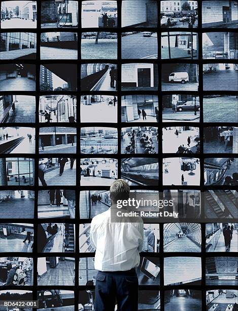 man watching wall of surveillance screens - paranoia fotografías e imágenes de stock
