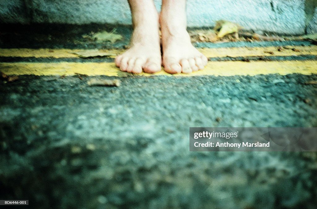 Bare-footed man on yellow lines at side of road