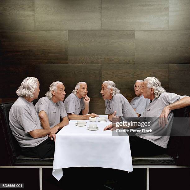 clones of mature man at table - cloning stock-fotos und bilder