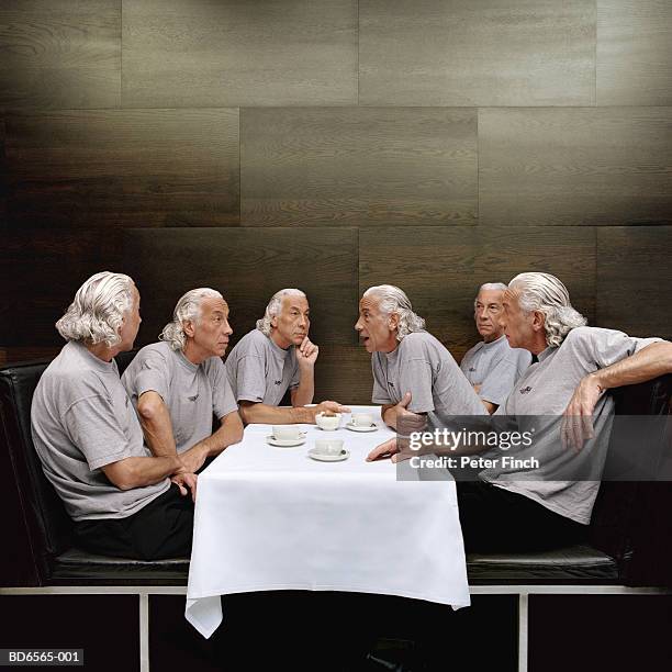 clones of mature man at table - klonen stockfoto's en -beelden