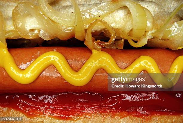 hotdog with mustard, tomato ketchup and onions, close-up - tomatenketchup stockfoto's en -beelden