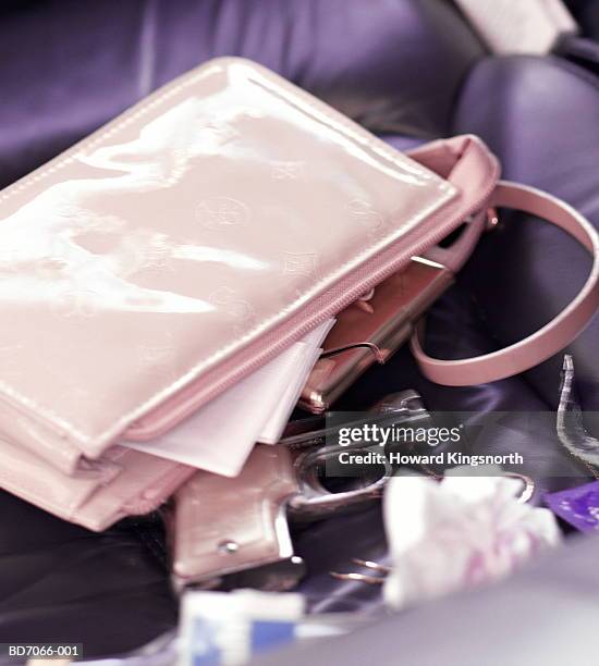 handbag, contents and gun on car seat, close-up - pink pistols stock-fotos und bilder