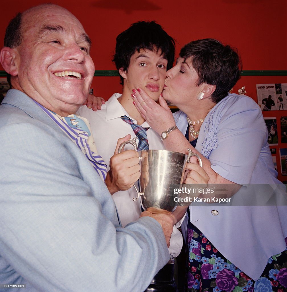 Parents with son holding trophy, portrait, close-up