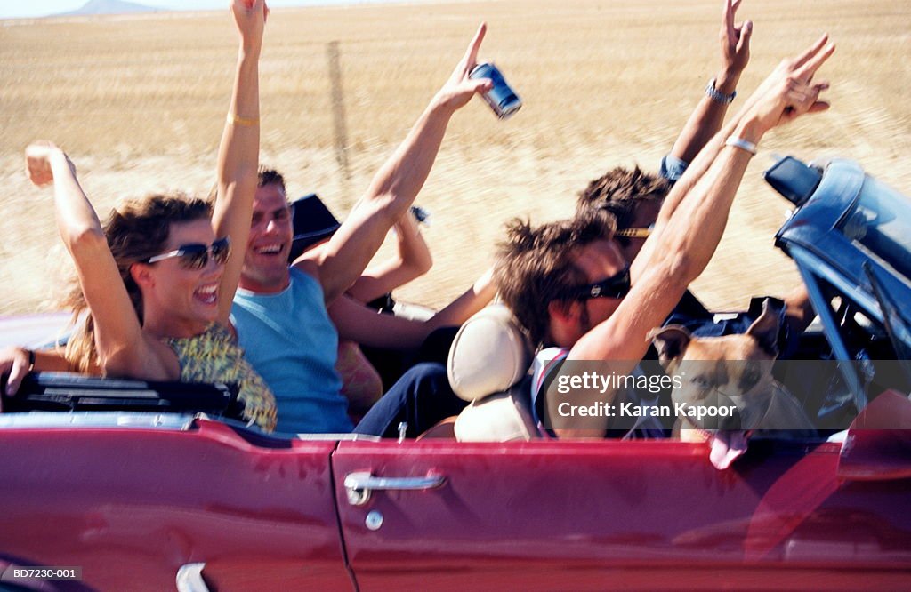 Group of people in convertible, arms in the air, close-up