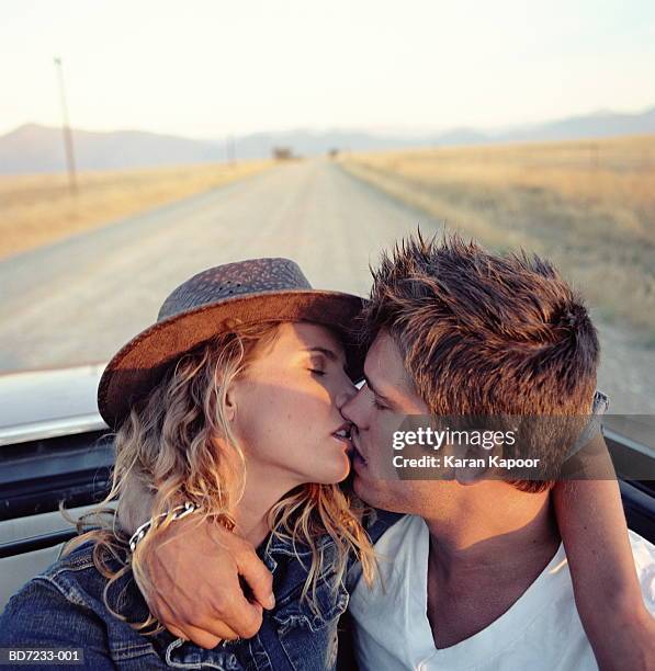 young couple kissing in back of convertible, close-up - beso en la boca fotografías e imágenes de stock
