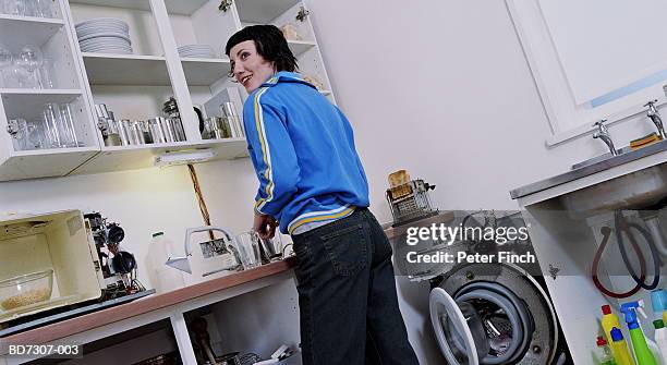 young woman in kitchen with stripped down appliances - buanderie photos et images de collection