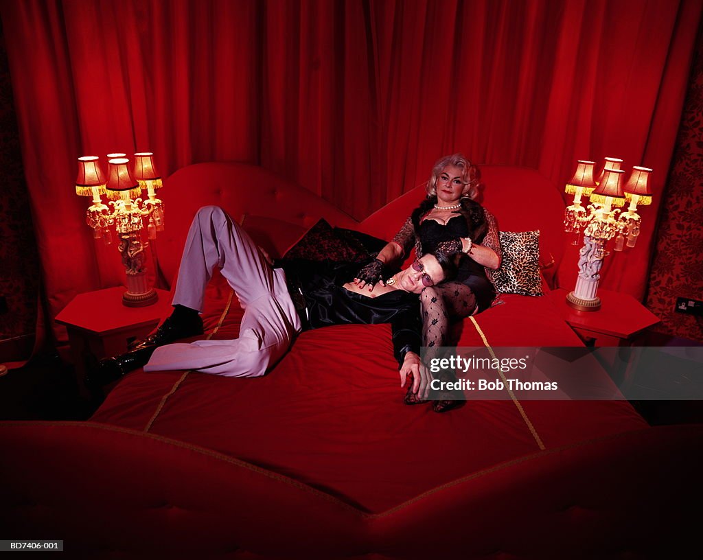 Mature woman and younger man reclining on bed, portrait