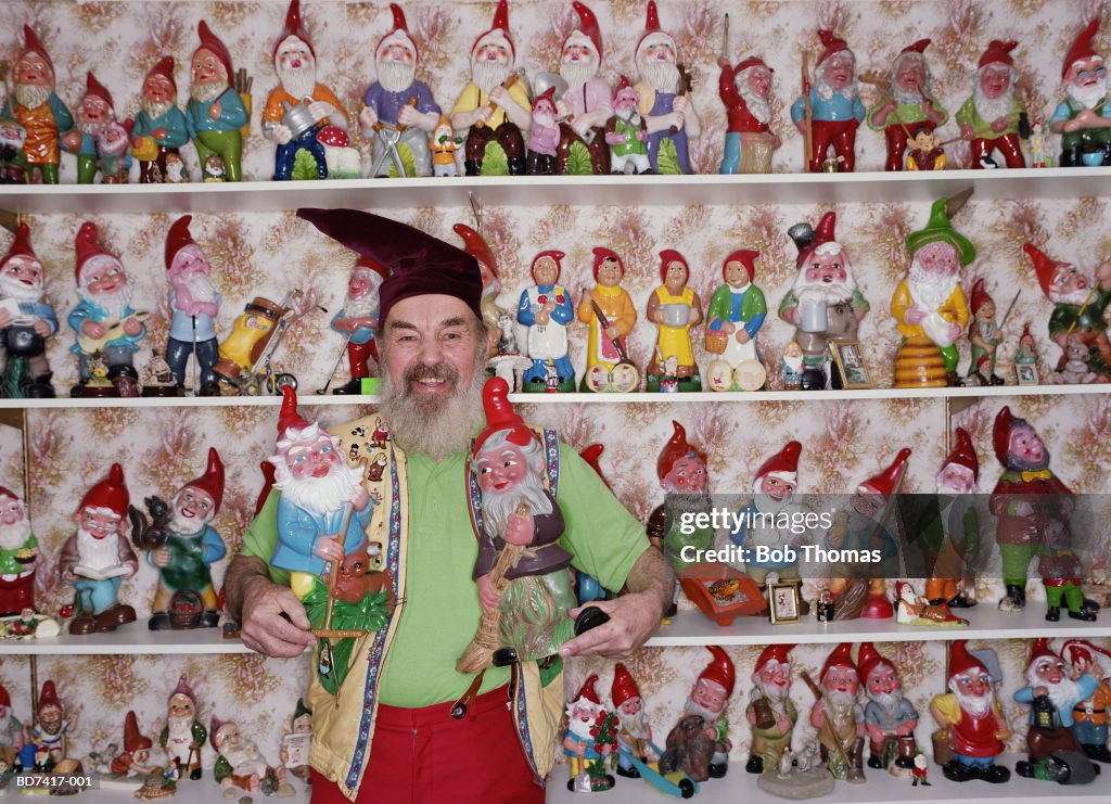 Mature man dressed as gnome with collection of gnomes, portrait