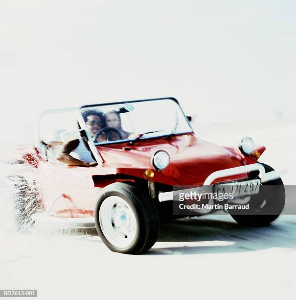 young couple in beach buggy driving along beach - dune buggy stock pictures, royalty-free photos & images