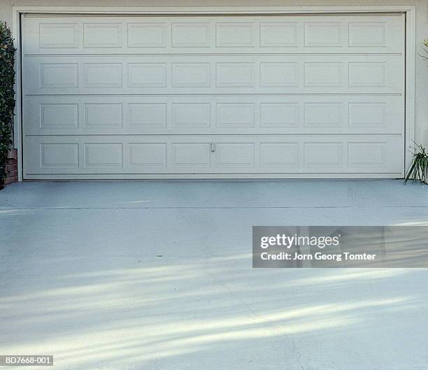 garage door and driveway - autobergplaats stockfoto's en -beelden