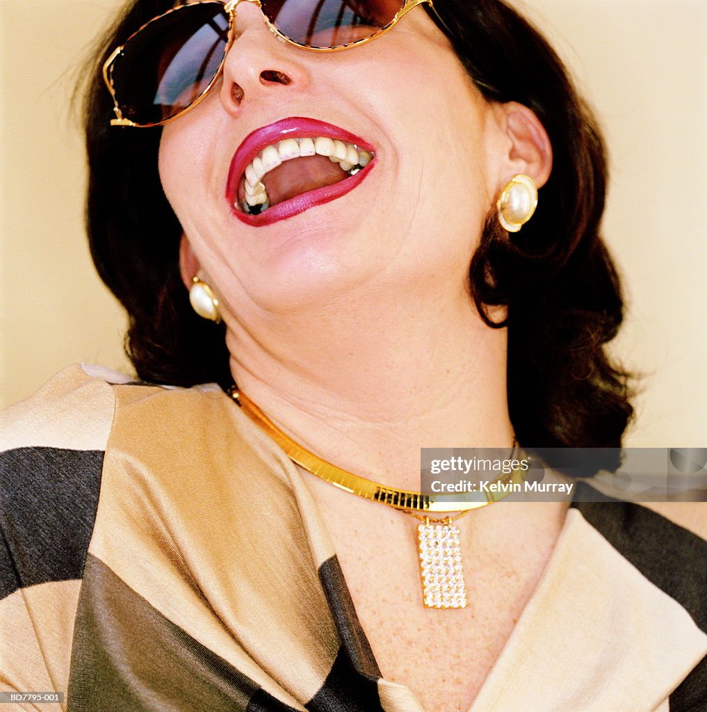 Mature woman wearing sunglasses, laughing, close-up