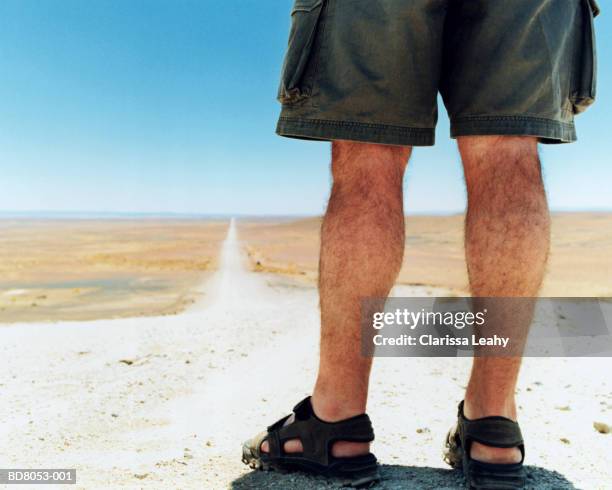 man standing on country road, rear view (low-section) - hairy back man - fotografias e filmes do acervo