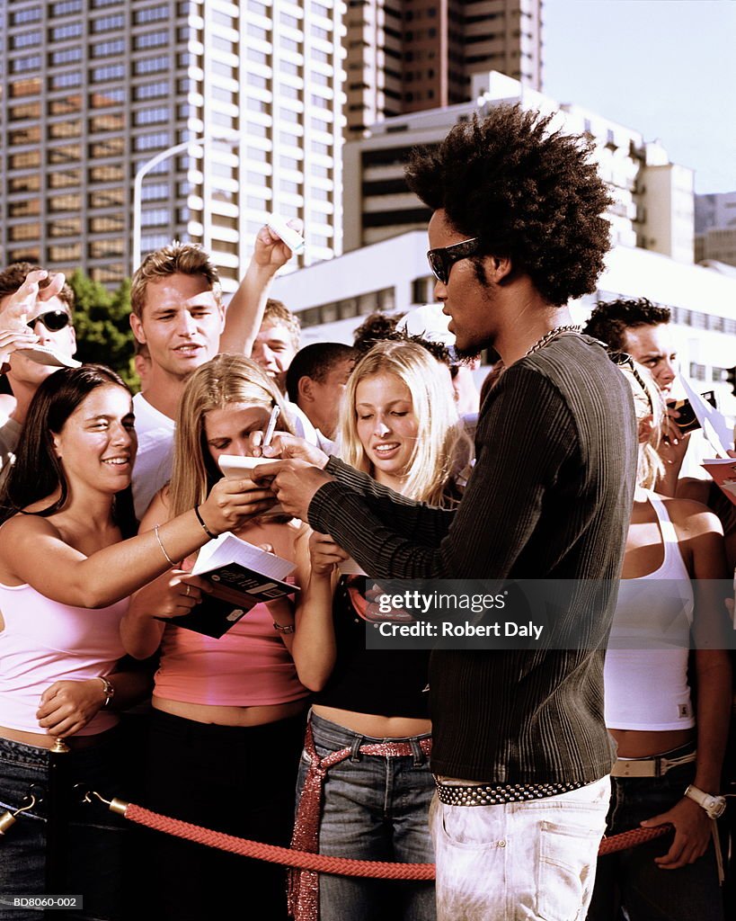 Young man signing autographs for fans
