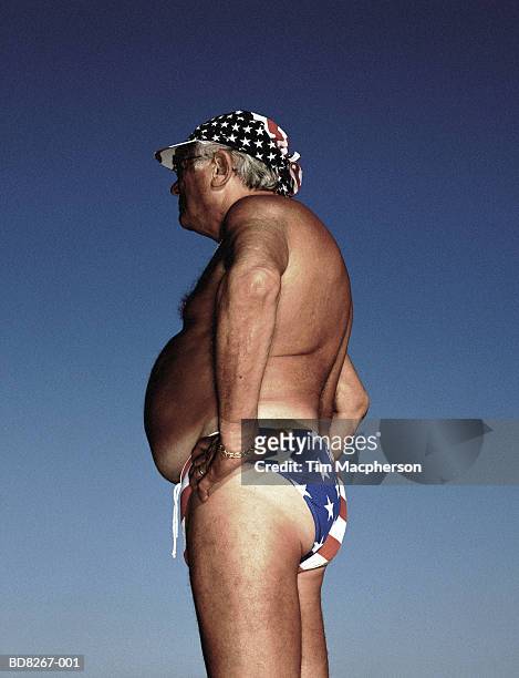 mature man wearing 'stars and stripes' swimming trunks, profile - tre quarti foto e immagini stock