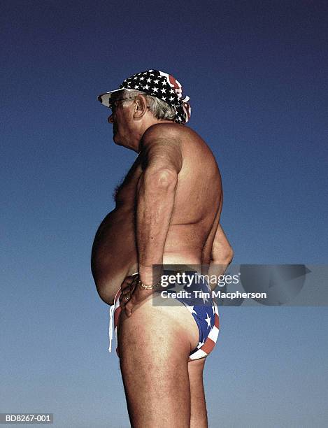 mature man wearing 'stars and stripes' swimming trunks, profile - speedo stockfoto's en -beelden