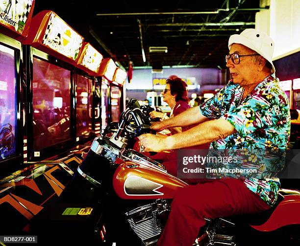 elderly man and woman on motorcycle arcade games - amusement arcade stock-fotos und bilder