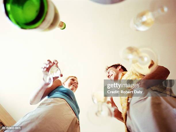 couple holding glasses, bottle of wine on table, view from below - untersicht stock-fotos und bilder