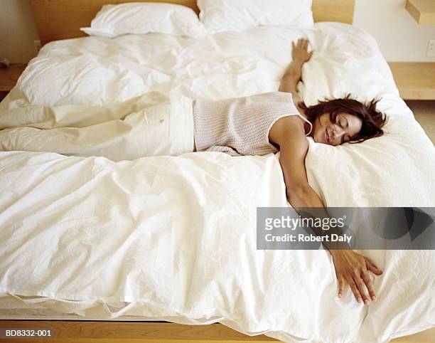 woman sprawled on bed, smiling - duvet stock pictures, royalty-free photos & images