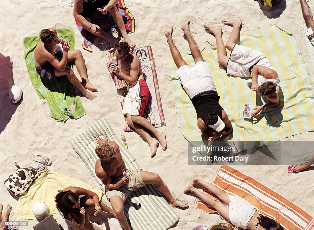 Group of people eating and drinking on beach, overhead view