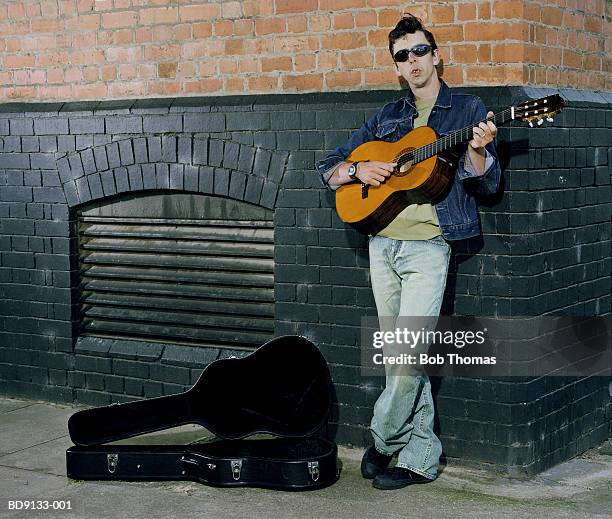 man busking with acoustic guitar, leaning against wall - busker 個照片及圖片檔