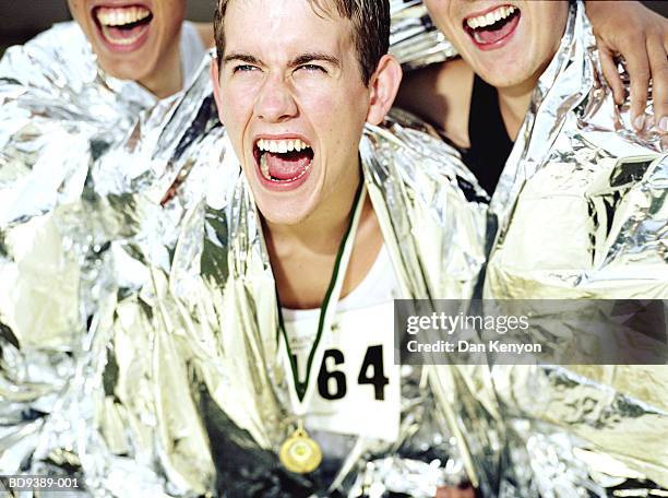 three runners wrapped in foil blankets, cheering, close-up - sporthesje stockfoto's en -beelden