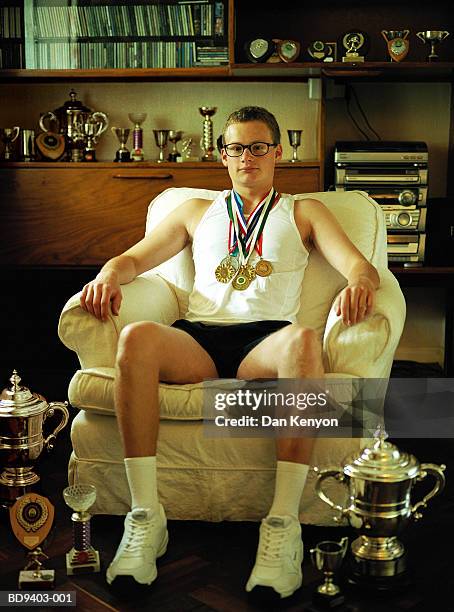 young man wearing medals, surrounded by trophies, portrait - médaille récompense photos et images de collection