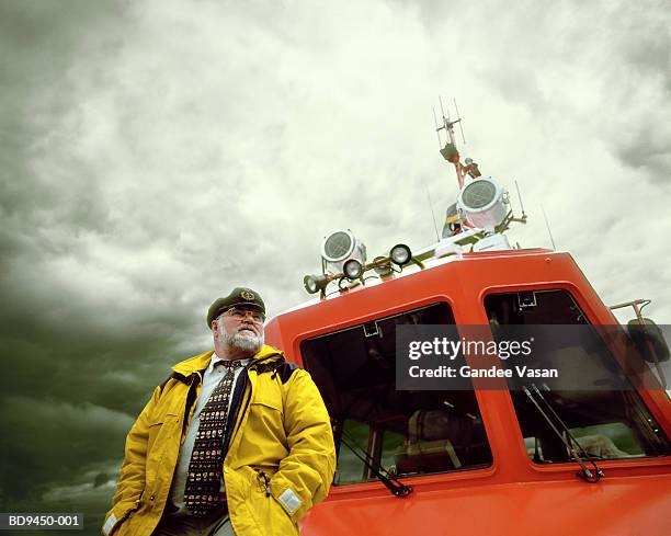 coastguard standing by cabin of lifeboat - guardacostas fotografías e imágenes de stock