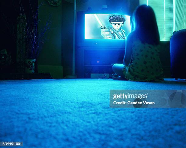 young girl (8-10) sitting on floor watching television, rear view - girl sitting on floor stock-fotos und bilder