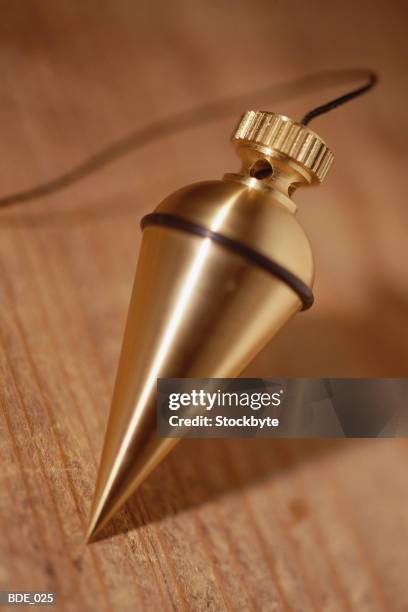 brass plumb bob at end of plumb line - schietlood-meetinstrument stockfoto's en -beelden