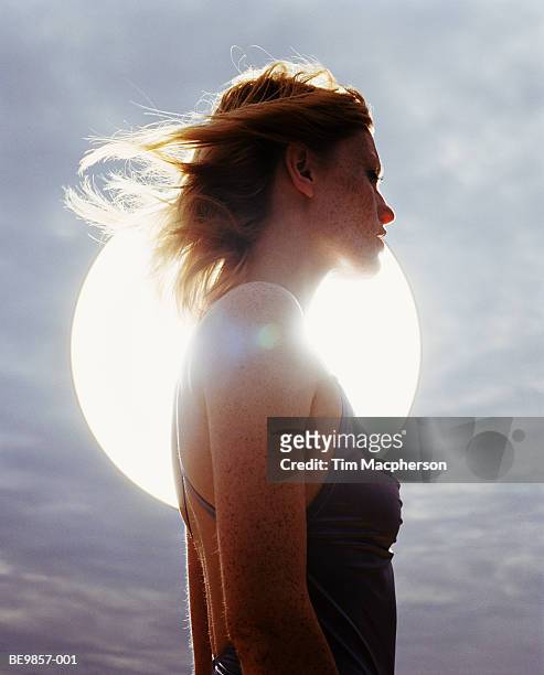 young woman standing in front of sun, backlit - espiritualidad fotografías e imágenes de stock