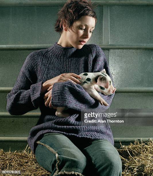 young woman holding piglet, close-up - ferkel stock-fotos und bilder